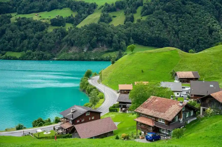 Is the Swiss Travel Pass Worth It for Americans? (Honest 2026 Review) Traditional wooden houses by a blue lake in Switzerland - Is the Swiss Travel Pass worth it? for this view